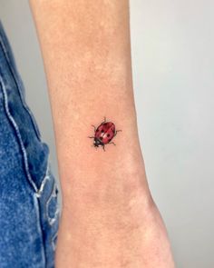 a ladybug tattoo on the wrist is shown in black and red colors,