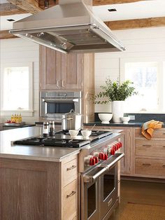 a kitchen with wooden cabinets and stainless steel stove top oven, dishwasher, and range hood