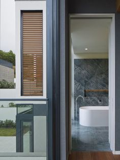 an open door leading to a bathroom with a large tub in the center and wooden slats on the walls