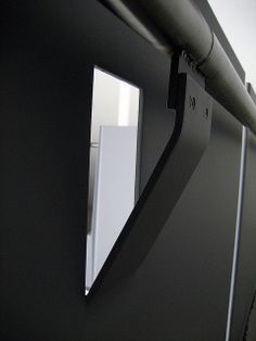 the reflection of a white refrigerator in a black cabinet door with an angled mirror on it's side