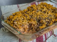 a casserole dish with noodles and meat in it on a red and white towel