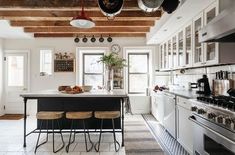 a kitchen with white cabinets and an island in the middle, surrounded by hanging pots and pans