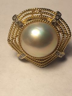 A beautiful Mave Pearl (genuine, cultured) set in 14K gold ring surrounded by diamonds. 4 strips of 3 diamonds each total 12 diamonds. The gold banding has a bend to it in the centers, which isn't necessarily shown the best in the photos. Beautifully made elegant ring great for anyone special Formal Yellow Gold Pearl Ring With Diamond Accents, Timeless Gold Pearl Ring With Diamond Accents, Gold Oval Pearl Ring With Diamond Accents, Pearl And Diamond Ring, Labradorite Ring, Elegant Ring, 14k Gold Ring, Gold Pearl, Wire Wrapped Jewelry