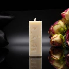 a candle that is sitting on a table with some flowers in front of it and the words light candles to save time