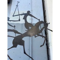 a metal artwork depicting a man riding a horse holding a bow and arrow on the side of a building