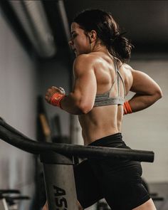 a woman is running on a treadmill in the gym with her hands behind her back