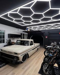 a white truck parked in a garage next to two motorcycles and a motorcycle rack on the wall