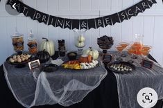 a table topped with lots of food next to a sign that says eat drink and be scary