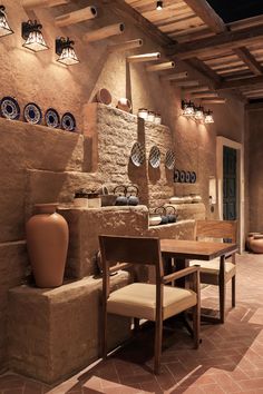 a dining room with stone walls and wooden tables in the center, surrounded by vases