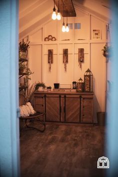 a room that has some lights hanging from the ceiling and wooden furniture in front of it