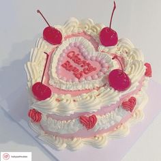 a heart shaped birthday cake with cherries on top