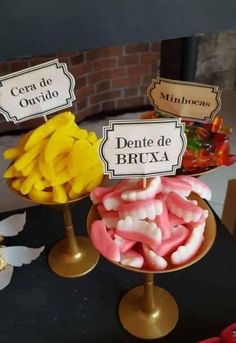 some candies are sitting on top of each other in gold dishes and signs that read, dentiste de bruxa