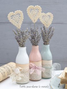 three vases with flowers in them sitting on a table next to books and papers