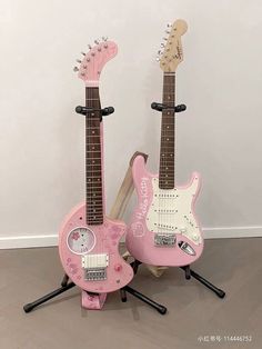 two pink guitars sitting on top of each other in front of a white wall and floor