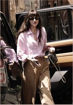 a woman in pink shirt and khaki pants stepping out of a black car