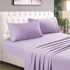 a bed with purple sheets and pillows on it