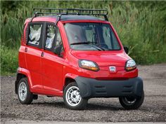 a small red car driving down a dirt road