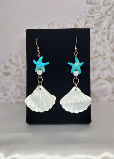 Add a touch of seaside charm to your look with these stunning Turquoise and white shell earrings featuring a whimsical starfish accent. These fun and stylish earrings are perfect for beach days, summer outings, or adding a pop of color to your everyday ensemble. Handcrafted with care, these earrings are sure to make a splash wherever you go. WHAT'S IN THE BOX: 1 pair of earrings. Any other items shown in picture are for staging and to show scale and are not included with purchase. Thank you for visiting my shop! White Starfish Pendant Ocean-inspired Jewelry, White Shell Jewelry With Starfish Charm, White Ocean-inspired Jewelry With Starfish Charm, Ocean-inspired White Jewelry With Starfish Charm, White Starfish Charm Earrings, White Starfish Charm Earrings For Gift, White Starfish Charm Earrings As Gift, Ocean-inspired Starfish Charm Earrings, White Starfish Shell Gift