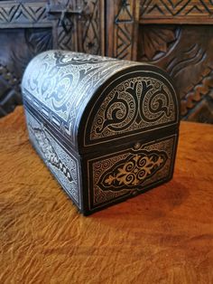 an ornate metal box sitting on top of a wooden table