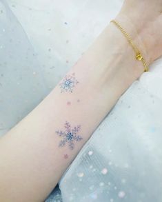 a snowflake tattoo on the arm of a woman's left arm and wrist