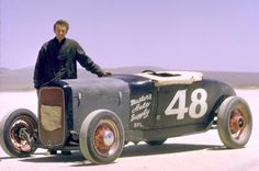 a man standing next to an old race car