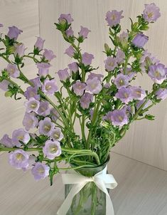 a glass vase filled with purple flowers on top of a table