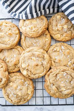 a bunch of cookies sitting on top of a cooling rack next to a black and white towel