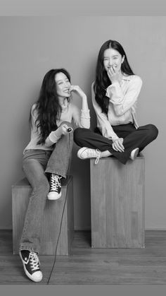 two young women sitting on top of wooden blocks