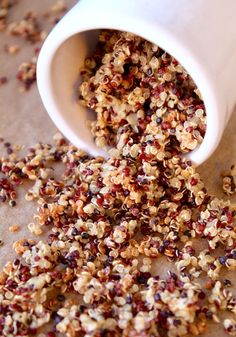 granola spilling out of a white cup on top of a piece of parchment paper