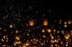 many lit up lanterns floating in the air at night with lots of lights on them