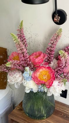 a vase filled with lots of pink and white flowers on top of a wooden table