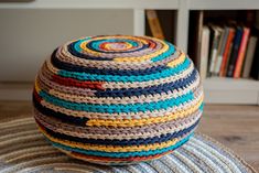 a multicolored round crocheted pouff sitting on top of a rug