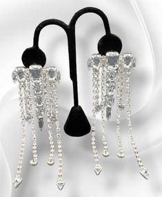 "Dripping with Ice": Dare to dazzle with our "Dripping with Ice" Earrings! These stunning earrings are fully adorned with blingy strands of dripping rhinestones, making you the star of any event. Elevate your style and sparkle with confidence! Approximately 5.5" long, 2 inches in width. Weight: approximately 1.3 ounces for the pair. Glamorous Silver Crystal Earrings With Rhinestone Fringe, Silver Crystal Earrings With Rhinestone Fringe, Long Drop Rhinestone Party Jewelry, Party Long Drop Rhinestone Jewelry, Silver Crystal Bling Earrings For Party, Silver Bling Crystal Earrings For Party, Party Jewelry With Rhinestones In Long Drop Shape, Party Jewelry With Long Drop Rhinestones, Glamorous Rhinestone Dangle Chandelier Earrings