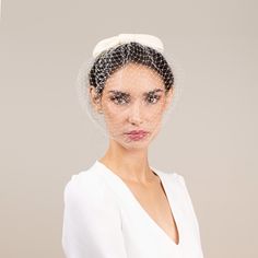 a woman wearing a birdcage veil over her head with a white shirt underneath