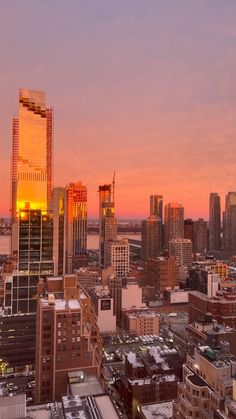 the sun is setting over an urban area with tall buildings and skyscrapers in the foreground