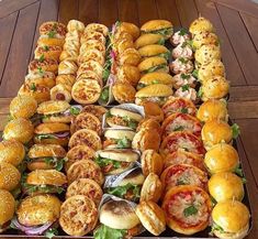 a large tray filled with lots of different types of sandwiches and doughnuts next to each other