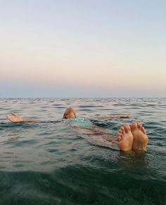 two people floating in the ocean with their feet up