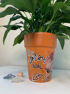 a potted plant with the words you grow girl on it next to some rocks