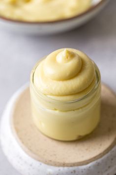 a jar filled with cream sitting on top of a white plate next to another bowl