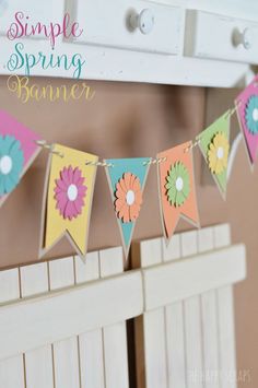 a bunting banner with flowers on it hanging from the side of a white dresser