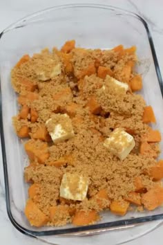 a glass dish filled with food on top of a white countertop next to a wooden spoon