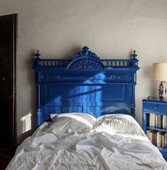 a bed with white sheets and blue headboard