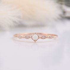 a white opal and diamond ring sitting on top of a table