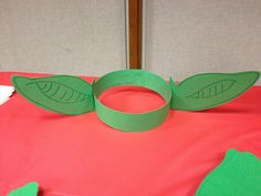 a paper plate sitting on top of a bed with two green leaves cut out of it