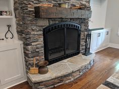 a stone fireplace in the middle of a room with wood flooring and built - in shelving