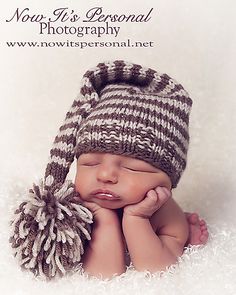 a newborn baby wearing a brown and white knitted hat