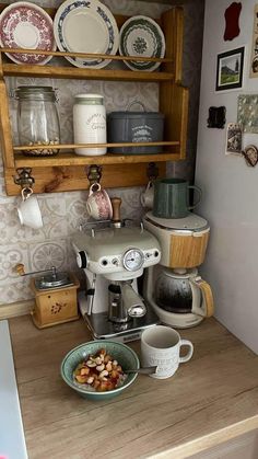 an old fashioned coffee maker on a kitchen counter with plates and cups in front of it