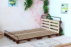 a bed frame made out of wooden pallets in front of a pink painted wall