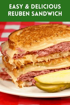 a sandwich with meat, cheese and pickle on a white plate next to a red checkered tablecloth