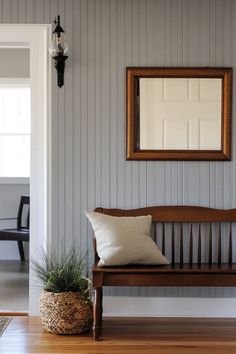 a wooden bench sitting in front of a mirror on the wall next to a potted plant